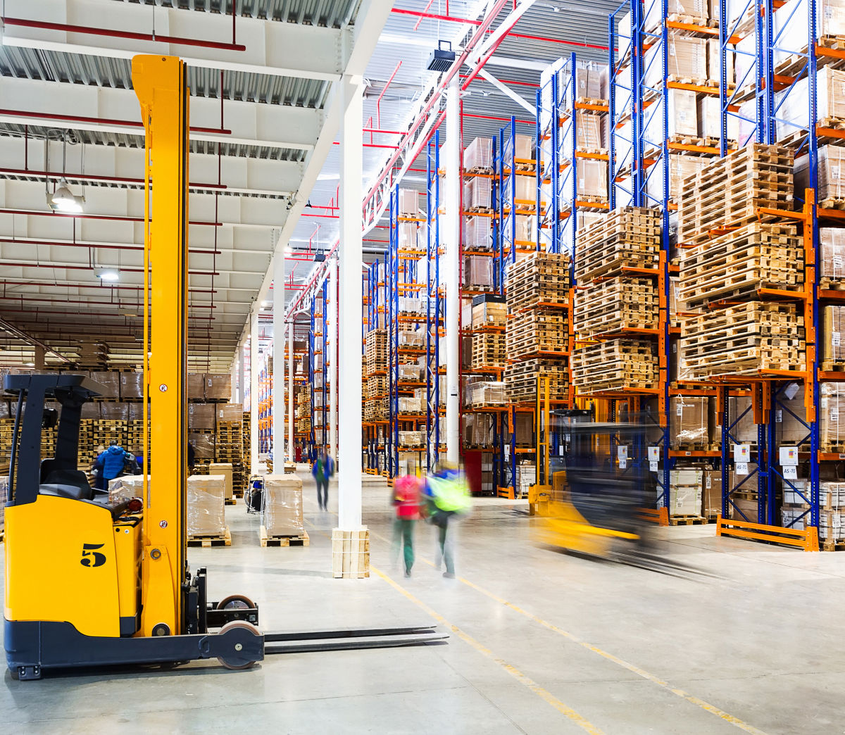 Interior of a busy warehouse with shelves of goods and a stationary forklift.